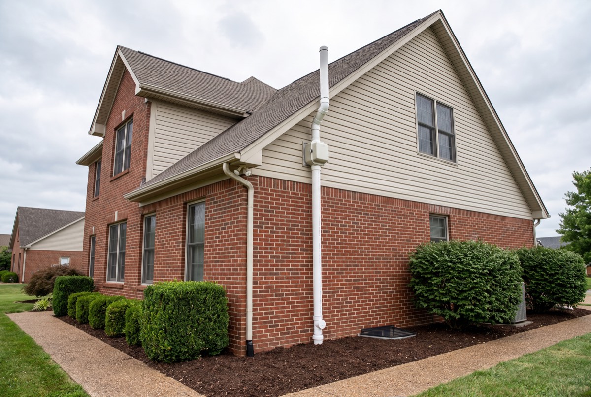 Exterior radon mitigation system pipe and fan on a brick Kentucky home